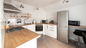 A modern kitchen with white cabinets, a stainless steel refrigerator, a microwave, and a gas stove. - Argyle Apart Hotel (London)