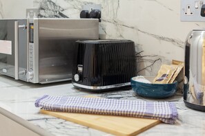 Una cocina con un tostador de acero inoxidable, un electrodoméstico negro y un tazón azul sobre la encimera.