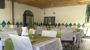 A dining area with tables set for a meal, chairs with white covers, and a decorative wall with a geometric pattern. - Richland Lodge Motel (Livingstone)