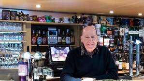 A bar area with shelves stocked with various bottles and glasses. - Morris Gardens Apartments (Inverurie)