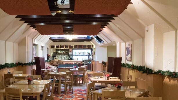 A restaurant with wooden tables and chairs, a bar area, and festive decorations. - Morris Gardens Apartments (Inverurie)