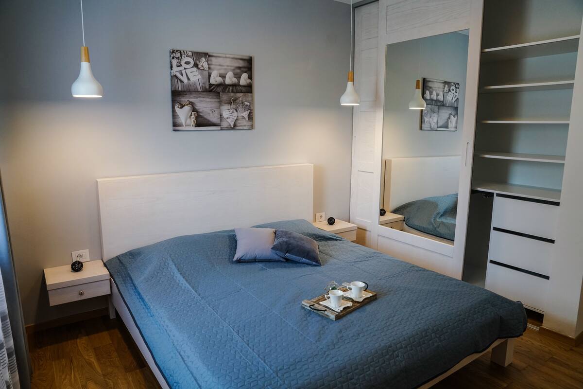 Ein ordentlich eingerichtetes Schlafzimmer mit einem großen Bett, Nachttischen, einem Kleiderschrank und Wandbildern.