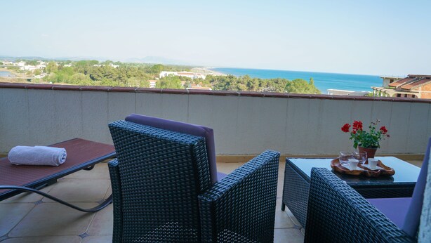 A balcony with wicker furniture, a towel, and a potted plant. - Apartments Bazar (Ulcinj)