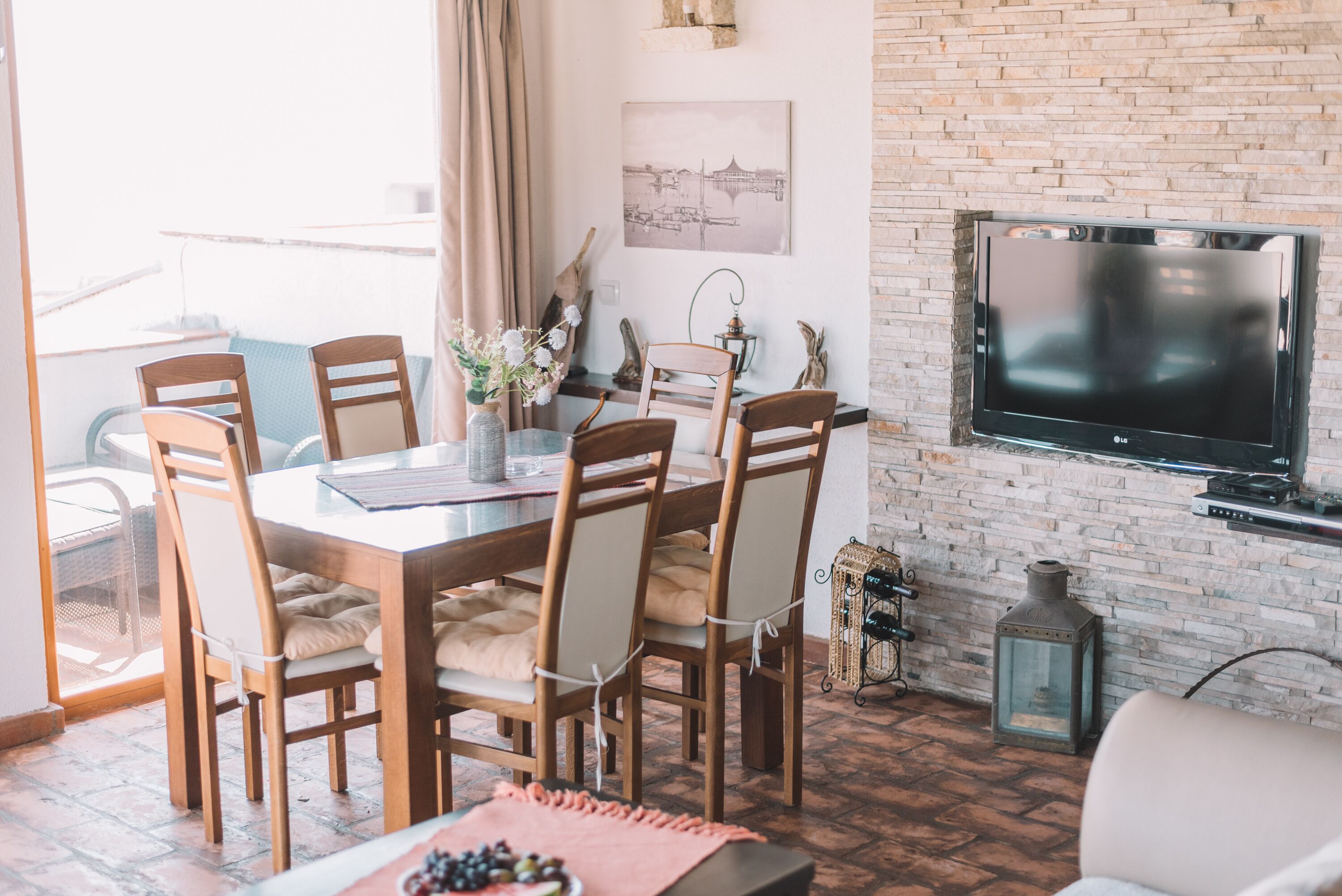 A dining area with a brick wall, a flat-screen TV, and a table set for six.