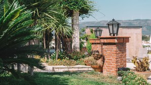 A garden with a brick wall, potted plants, and a lantern. - Apartments Bazar (Ulcinj)