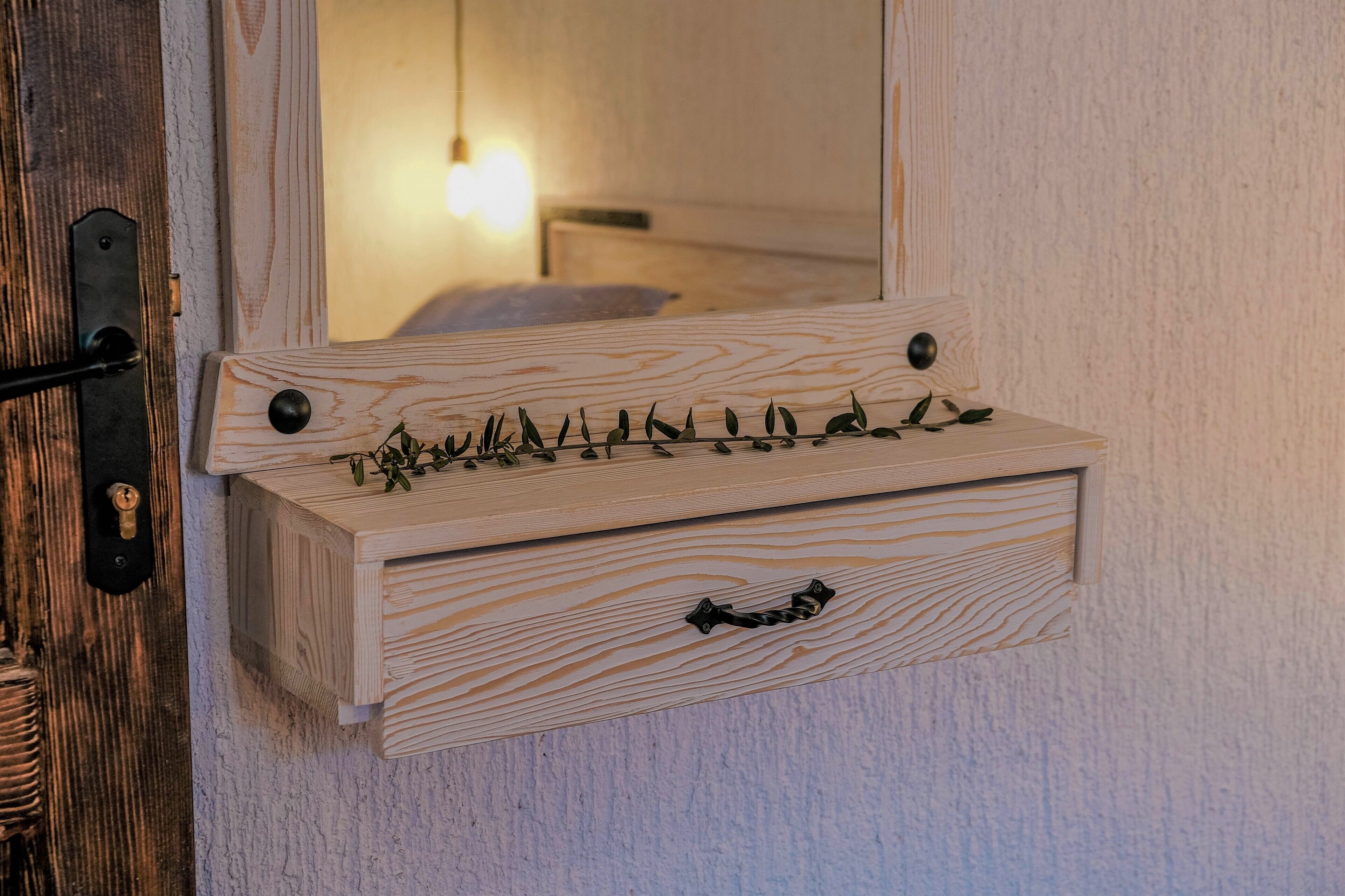 A wooden bedside table with a mirror, a small drawer, and a keyhole.
