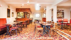 A restaurant with multiple tables and chairs, a bar area, and a patterned floor. - Godolphin Arms Hotel (Newquay)