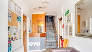 A hotel lobby with a reception desk, a staircase, and a leather couch. - Godolphin Arms Hotel (Newquay)