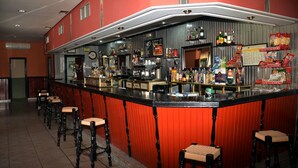 Zona de bar con taburetes, mostrador con varias botellas y una pizarra de menú.