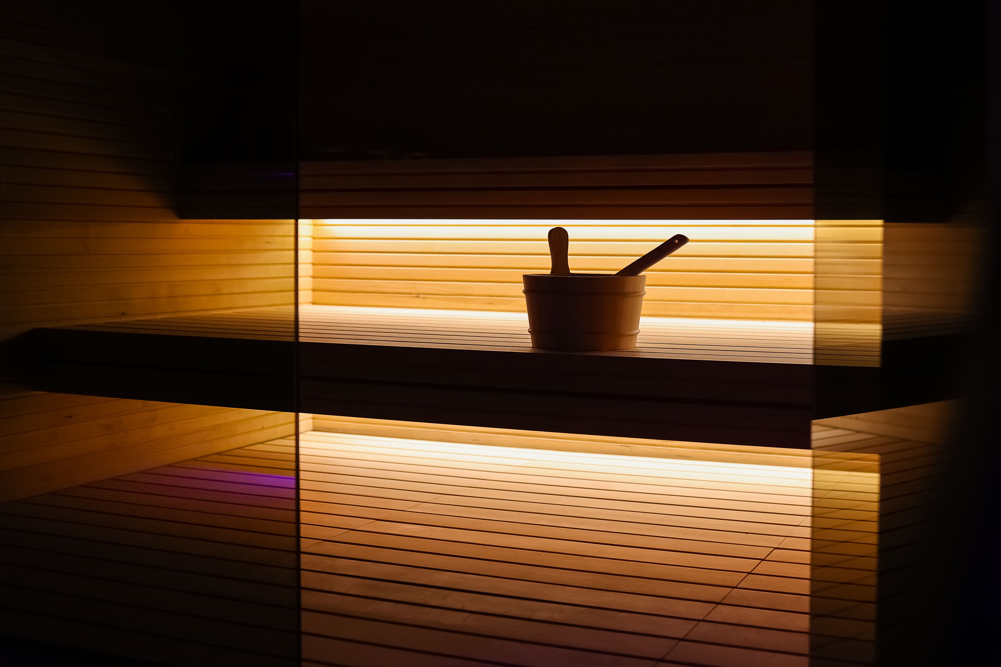 A wooden interior with a wooden bucket and a spoon on a shelf.