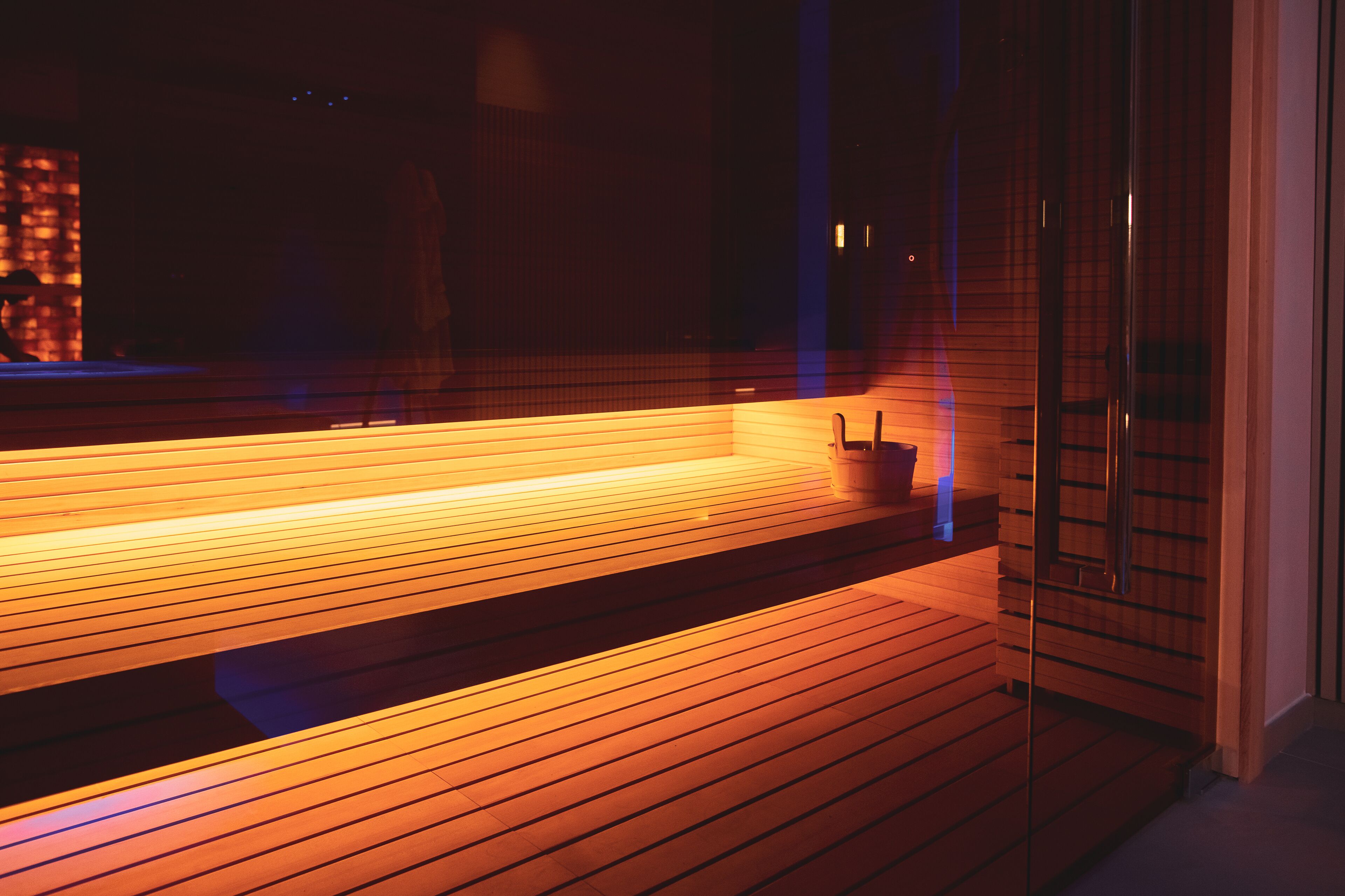 A modern interior with a wooden bench and a glass partition.