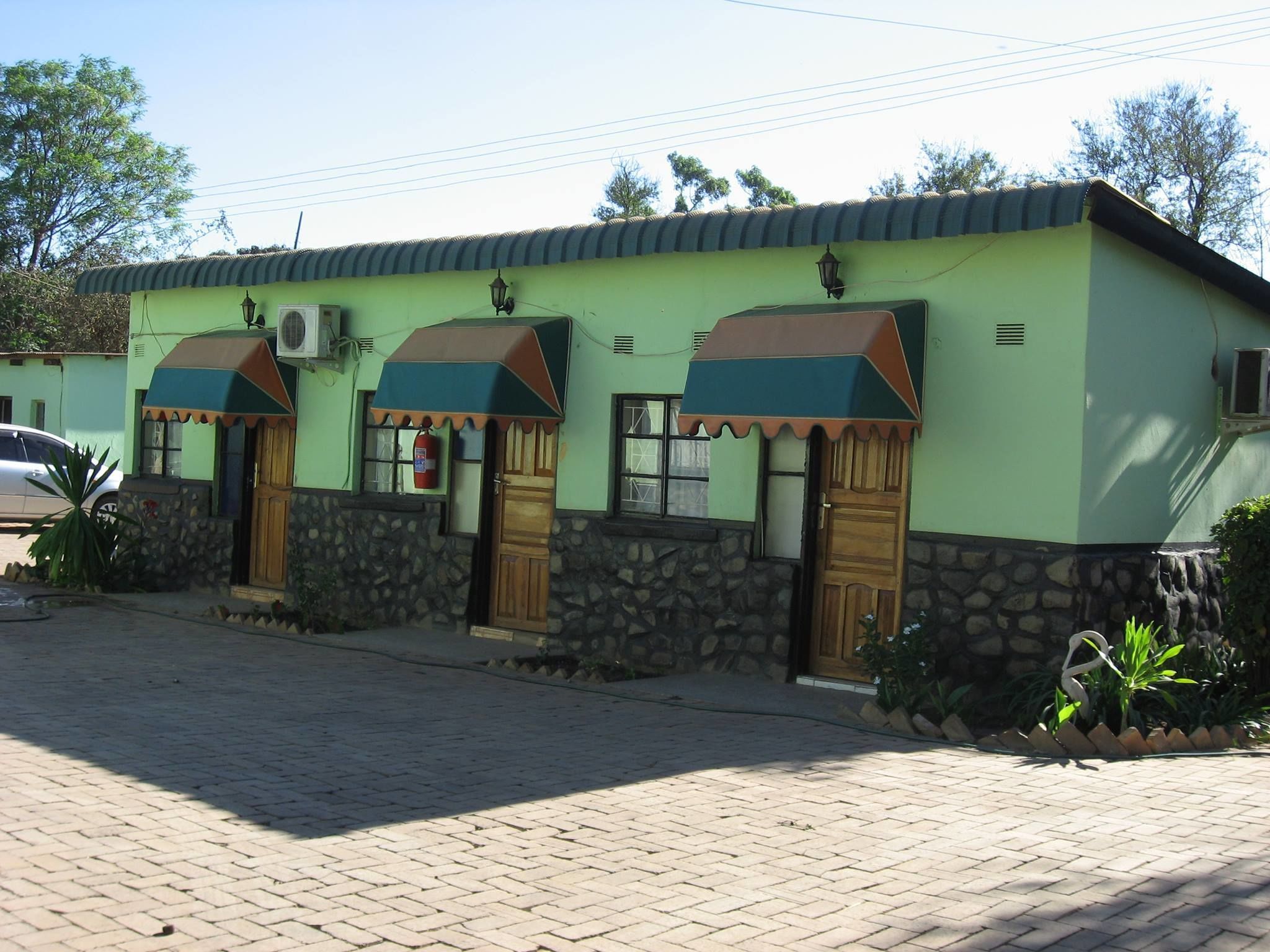 A two-story building with a green facade, stone accents, and awnings over the doors.