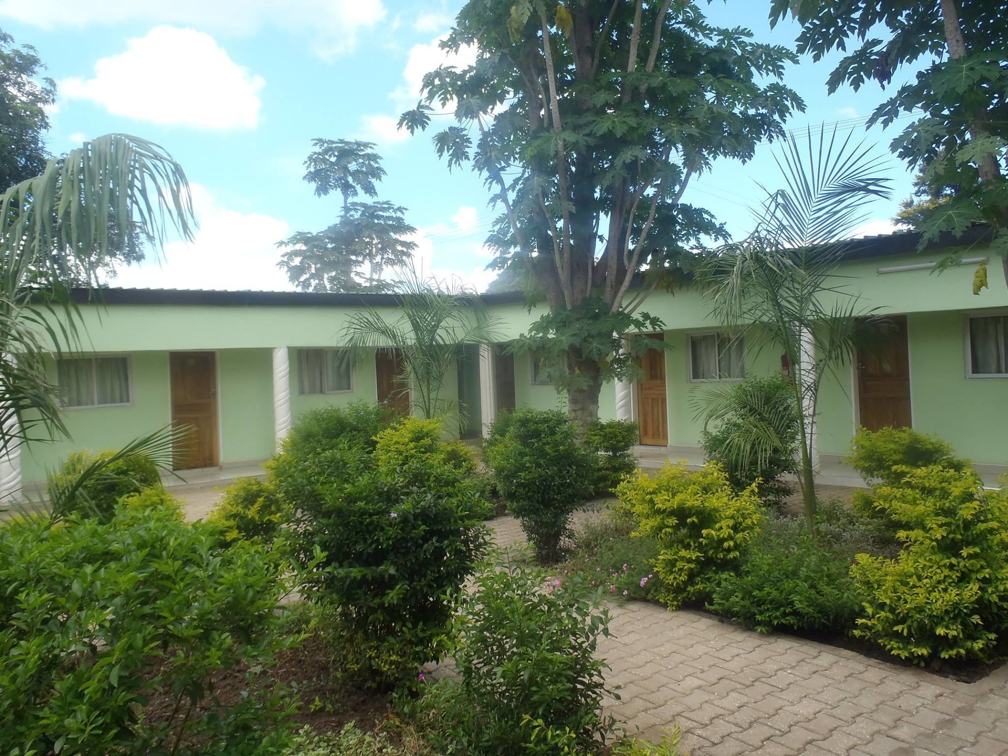 A building with multiple rooms, a paved courtyard, and lush greenery.