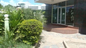 Um edifício com entrada coberta, porta de vidro e um caminho de pedra que leva à entrada.