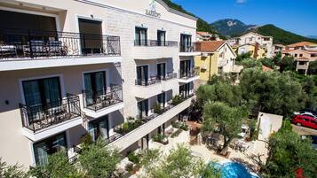 Un hôtel à plusieurs étages, doté de balcons, d’une piscine et offrant une vue sur les environs.