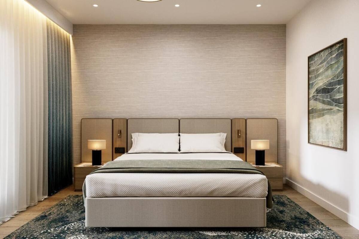 Een moderne hotelkamer met een groot bed, bedlampen, een hoofdbord en een groot abstract schilderij aan de muur.