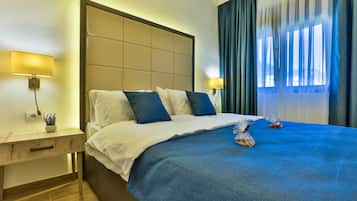 A hotel room with a large bed, a bedside table with a lamp, and a view of the outdoors through the window.