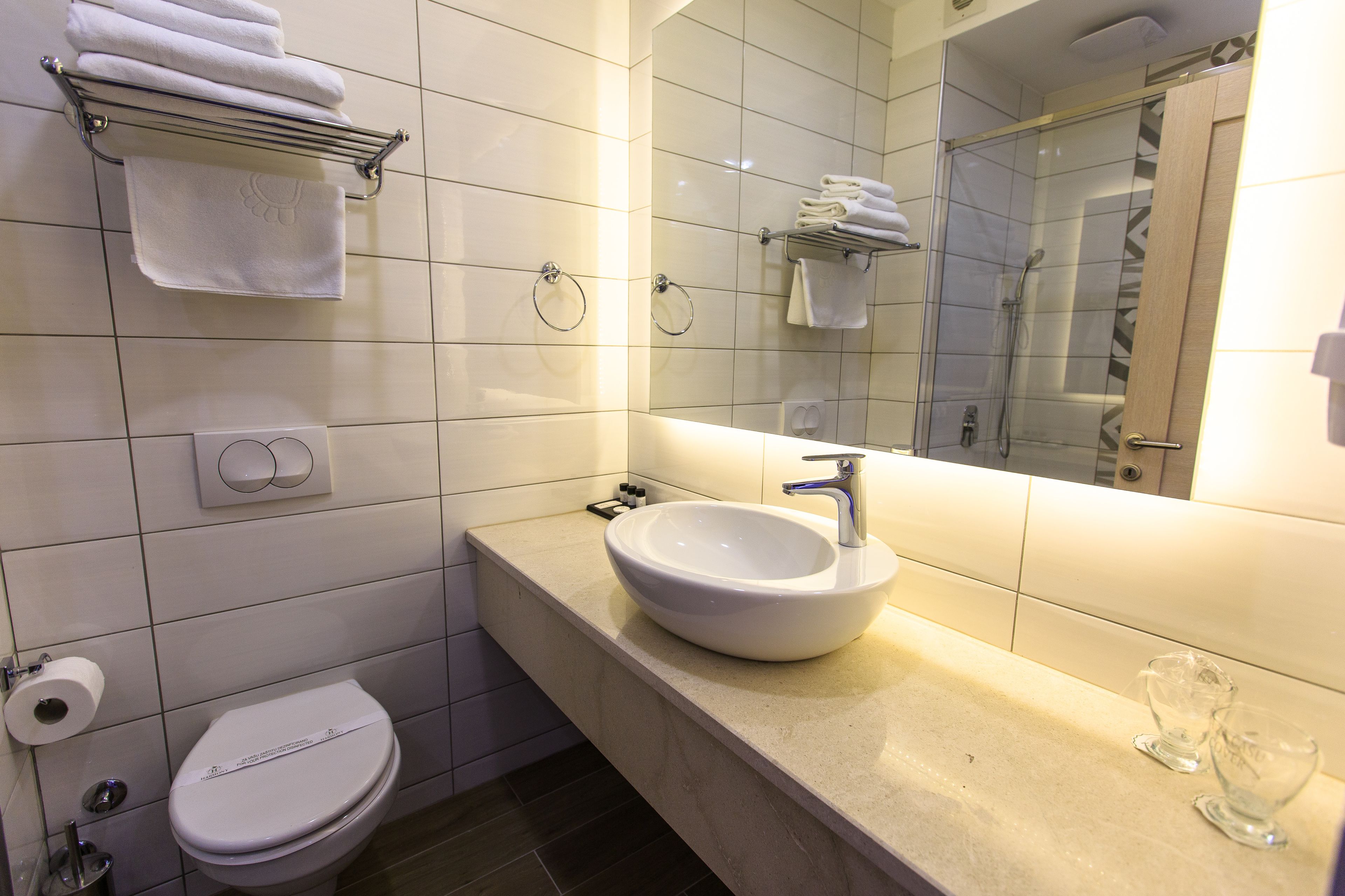 Un baño con un lavamanos blanco, un inodoro, un perchero para toallas y un espejo.