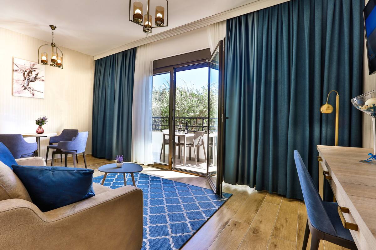 Een moderne woonkamer met een bank, een eettafel en een balkon met blauwe gordijnen.