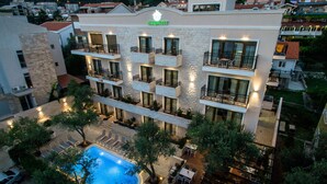 A hotel with a swimming pool, outdoor seating, and multiple balconies. - Hotel Harmony by Aycon (Petrovac)