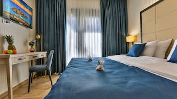Una habitación de hotel con cama, escritorio, silla, televisor y ventana con cortinas.