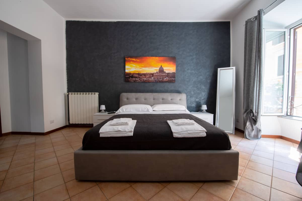 Ein modernes Schlafzimmer mit einem großen Bett, einem Nachttisch, einem Heizkörper und einem Fenster mit Vorhängen.