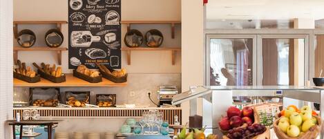 A bakery display with bread and pastries, a fruit bowl, and a wall with bakery-related illustrations.