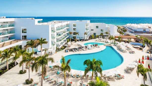 A resort with a large pool, palm trees, and a view of the ocean. - Hotel Lava Beach (Tías)