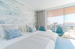 A modern hotel room with a large bed, a view of the sea, and a balcony with outdoor seating. - Hotel Lava Beach (Tías)