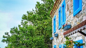 A stone pathway leading to a building with blue shutters and a stone facade. - Ataol Tatil Ciftligi (Bozcaada)