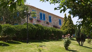 A stone building with blue window frames, surrounded by well-maintained hedges and a lawn. - Ataol Tatil Ciftligi (Bozcaada)