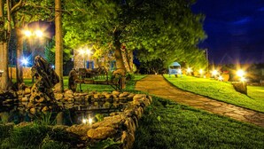 A nighttime garden with a pond, pathway, and gazebo. - Ataol Tatil Ciftligi (Bozcaada)