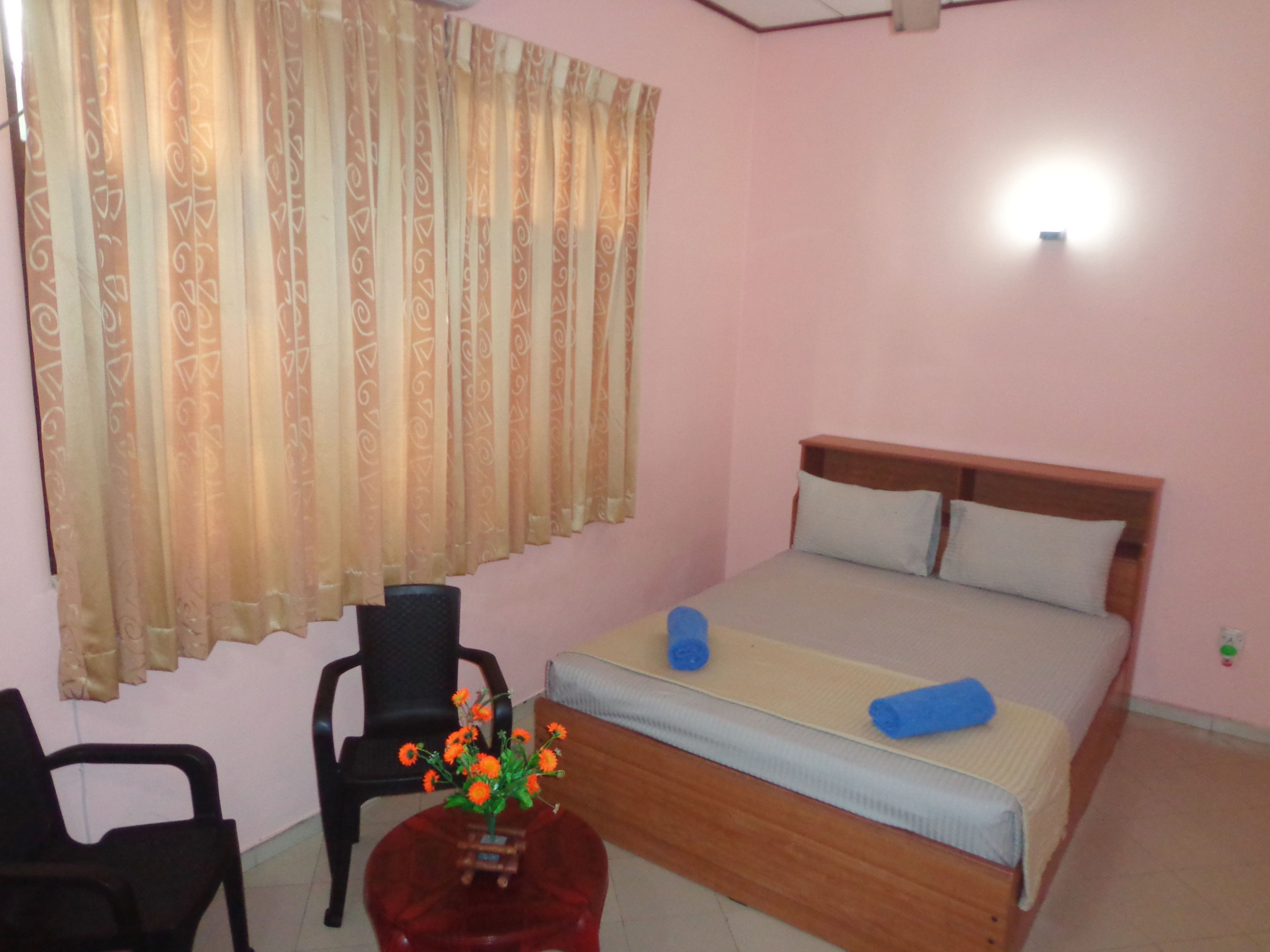 A bedroom with a bed, a chair, and a small table with flowers.