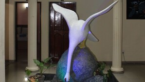 Un vestíbulo con una gran escultura de un ave, columnas y una pequeña fuente de agua.