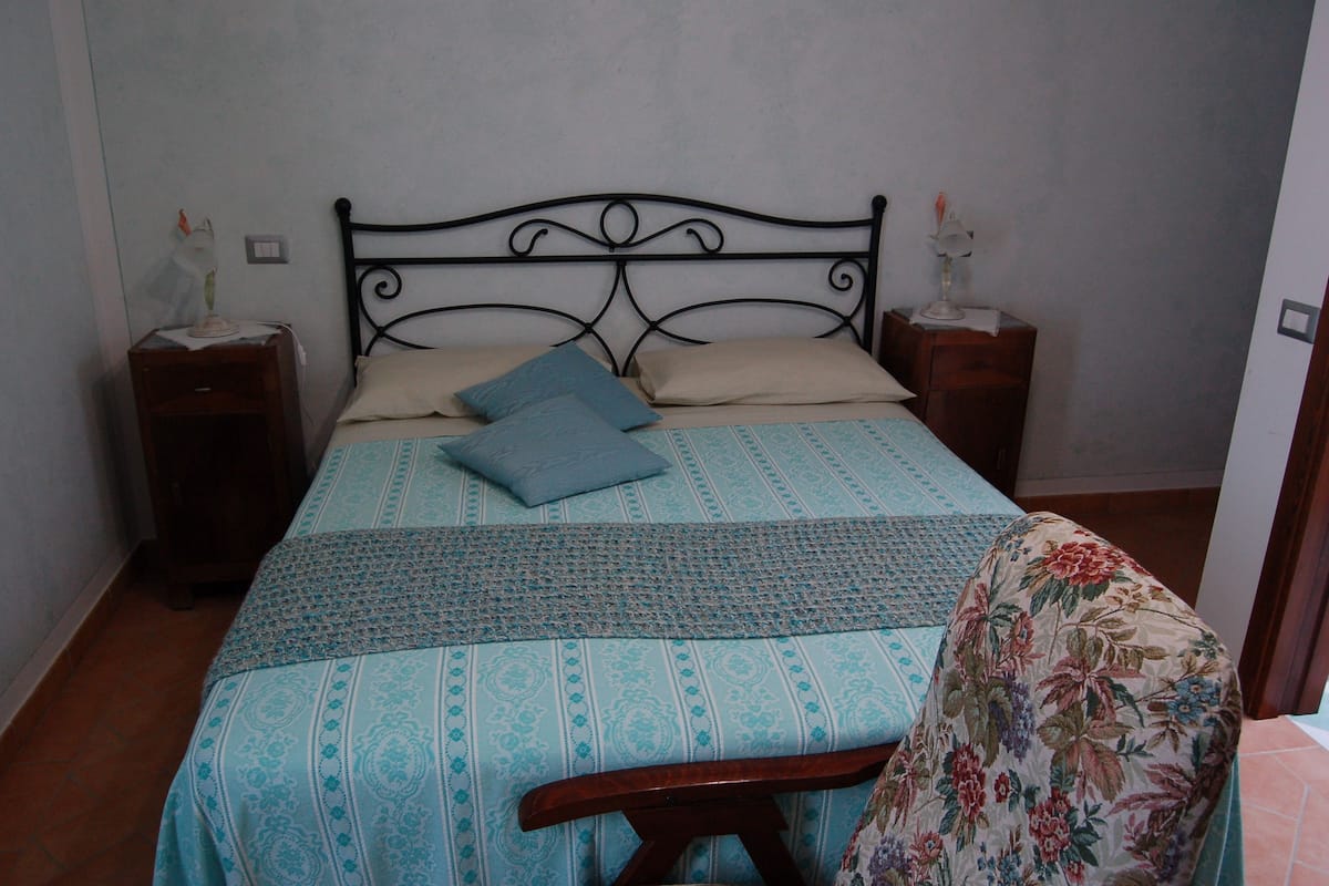 A bed with a patterned bedspread, two pillows, and a wooden headboard.