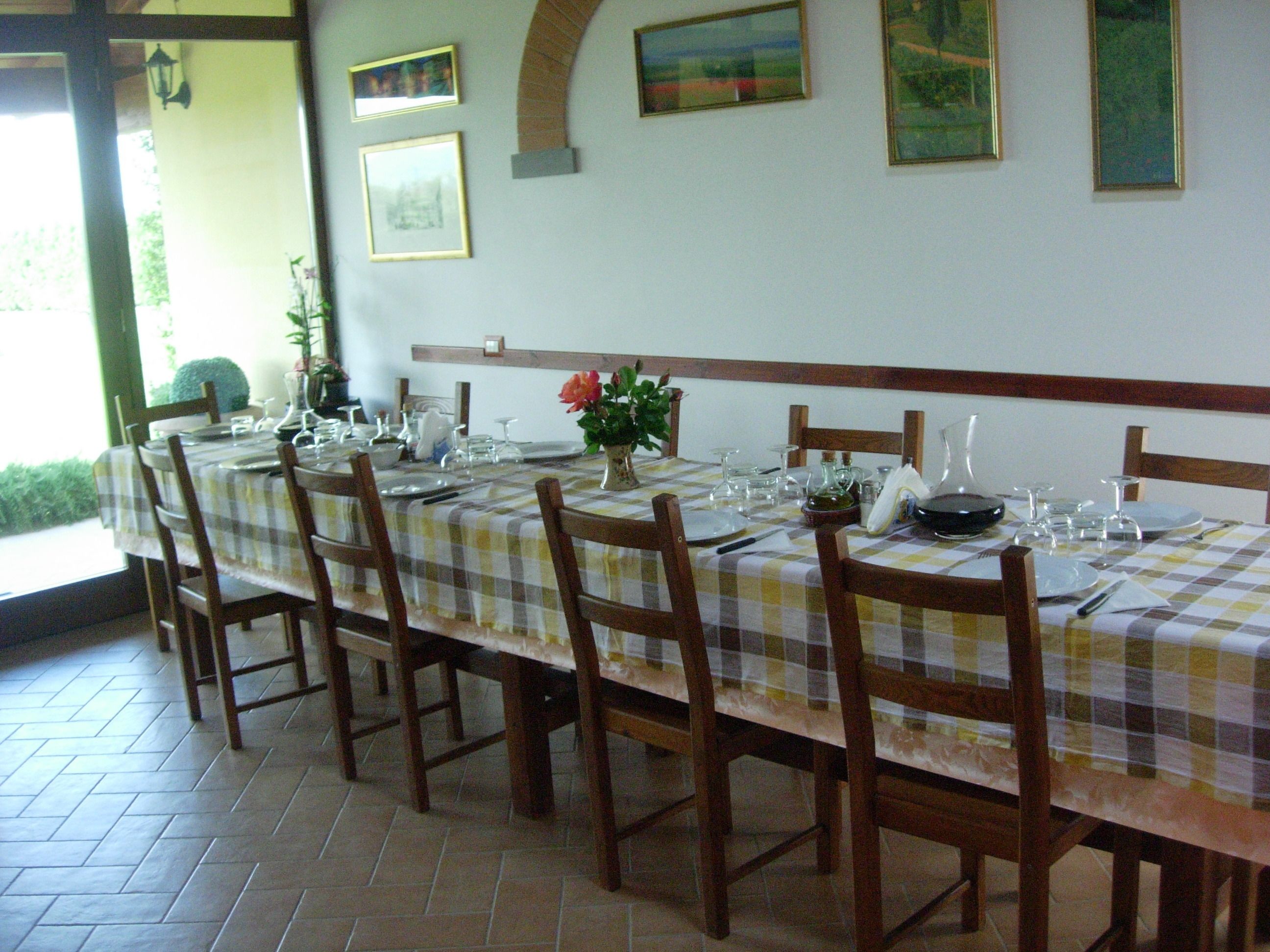 Un espace repas avec une longue table dressée pour six personnes, entourée de chaises en bois.