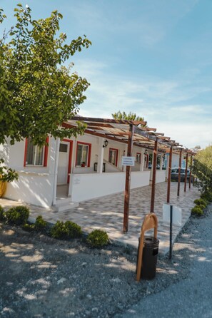 A row of white buildings with red trim and a pergola structure. - Mali Beach Apart Otel (Seferihisar)