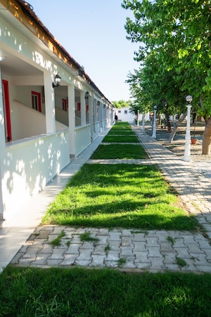 A pathway lined with white buildings, a grassy area, and trees. - Mali Beach Apart Otel (Seferihisar)