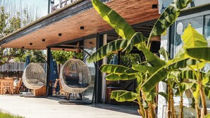 A building with a wooden deck, outdoor seating, and a garden area. - Mali Beach Apart Otel (Seferihisar)