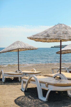 Ein Strand mit weißen Liegestühlen und Strohdächern.