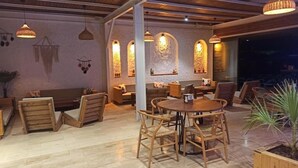 A cozy restaurant with wooden furniture, pendant lighting, and arched windows. - Mali Beach Apart Otel (Seferihisar)