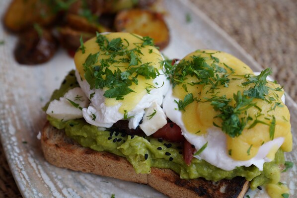 Ein Sandwich mit Avocado, Eiern und Grünzeug auf einer Brotscheibe.