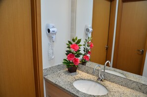 A bathroom with a granite countertop, a white sink, a mirror, and two hair dryers mounted on the wall. - Locar Caldas Casa da Madeira (Caldas Novas)