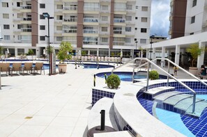 A rooftop pool area with multiple swimming pools, lounge chairs, and a staircase leading to an upper level. - Locar Caldas Casa da Madeira (Caldas Novas)
