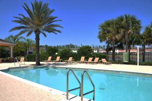A swimming pool with lounge chairs and palm trees.