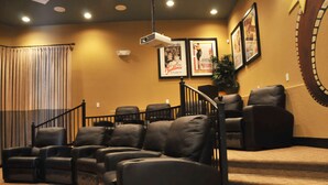 A home theater with a tiered seating arrangement, a projector, and framed movie posters on the wall. - Coral Cay Resort #2 - 4 Bed 3 Baths Townhome (Kissimmee)