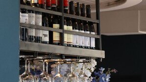 Eine Bar mit Weinregal, Gläsern und einer Vase mit Blumen.