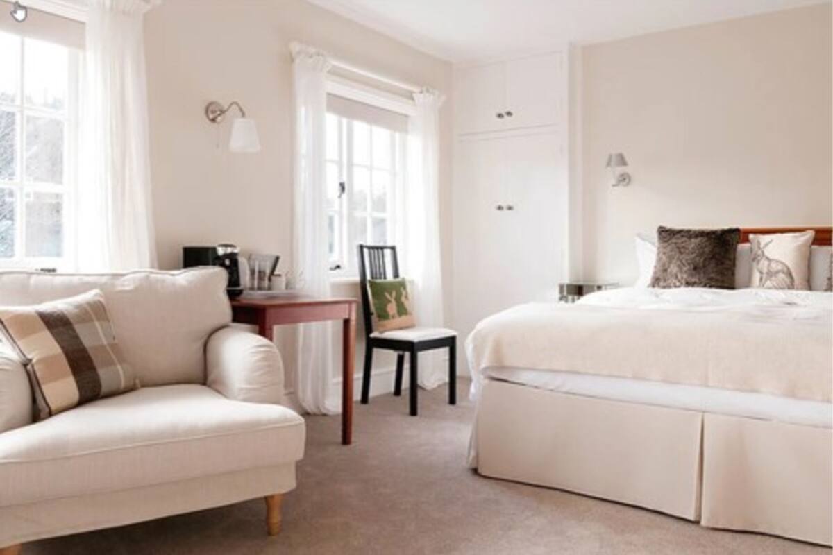 Quarto com cama, uma cadeira, uma mesinha e um guarda-roupa.