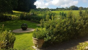 A well-maintained garden with a lawn, a decorative spherical sculpture, and a variety of shrubs and plants. - Hurtwood Hotel (Guildford)
