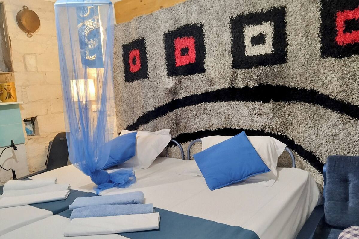 A bed with blue and white bedding, a blue canopy, and a wall with a geometric pattern.